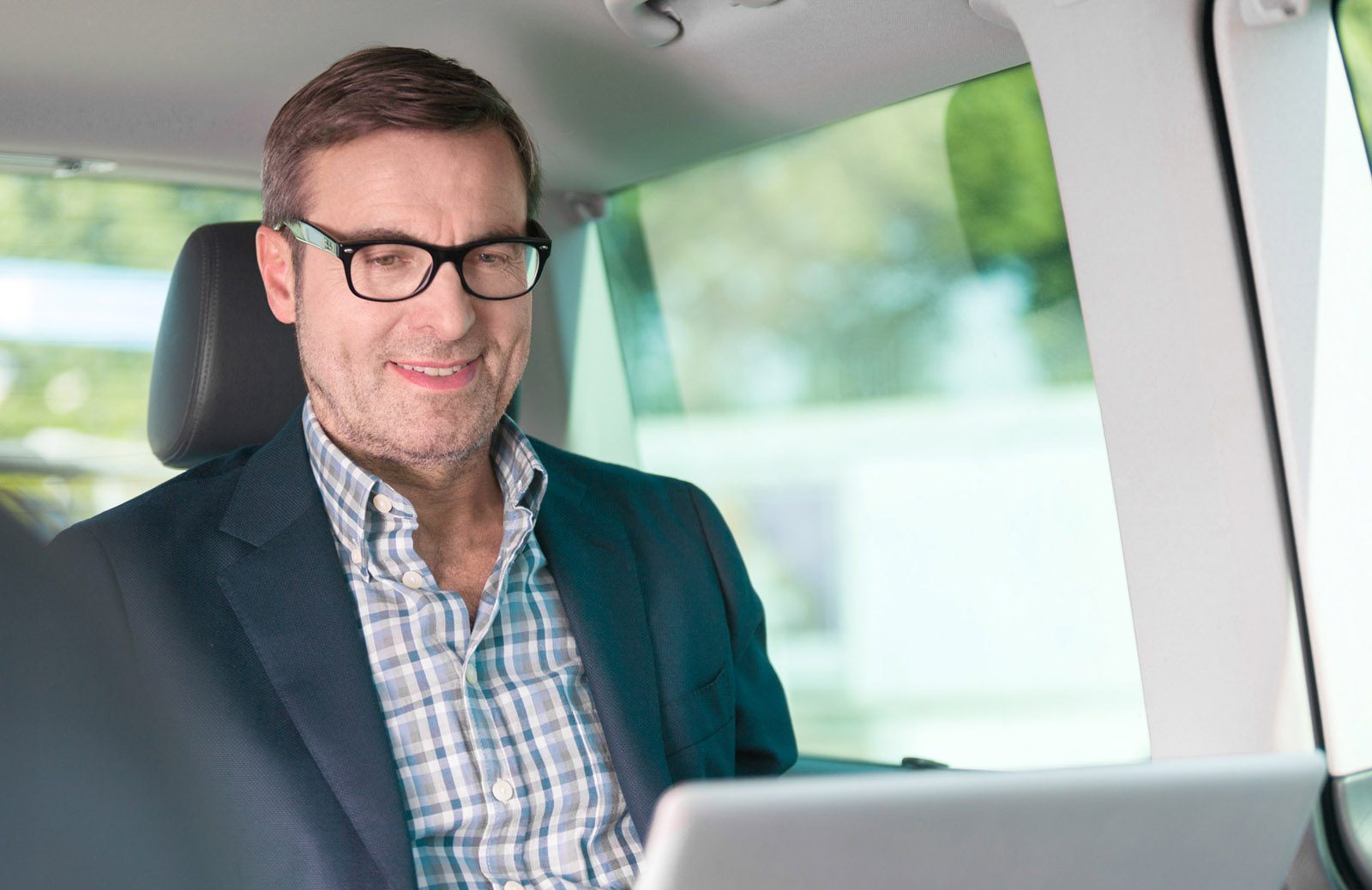 Mann schaut auf seinen Laptop und lächelt