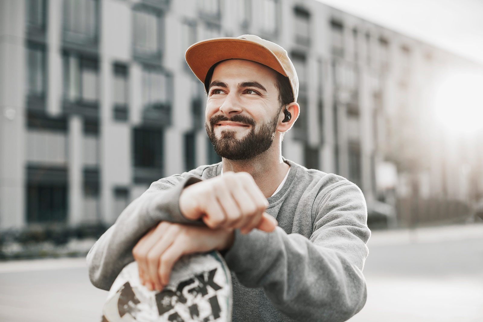 Skater lächelt und stützt sich mit den Händen am Skateboard ab