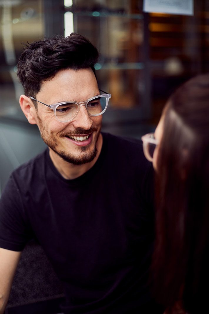 Mann mit transparenter Brille lächelt seine Frau an
